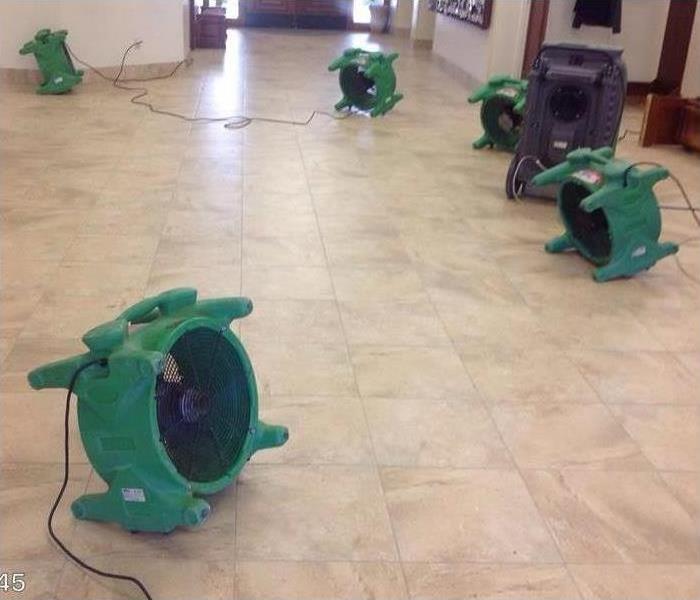 green air movers drying tile floor in commercial building