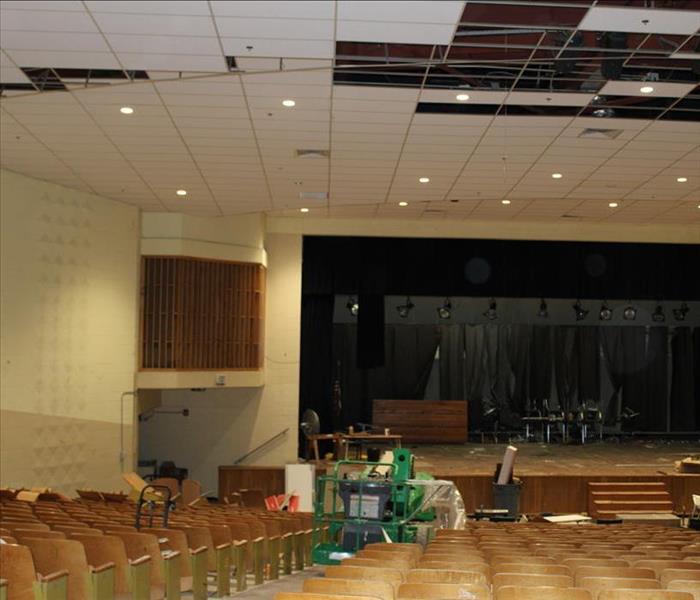 elementary school theatre damaged after fire, missing ceiling tiles, from the back of the room, looking onto auditorium