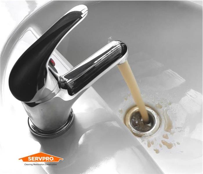 faucet pouring dirty sewer water out of the spout, silver in left corner above the sink, orange SERVPRO logo in corner