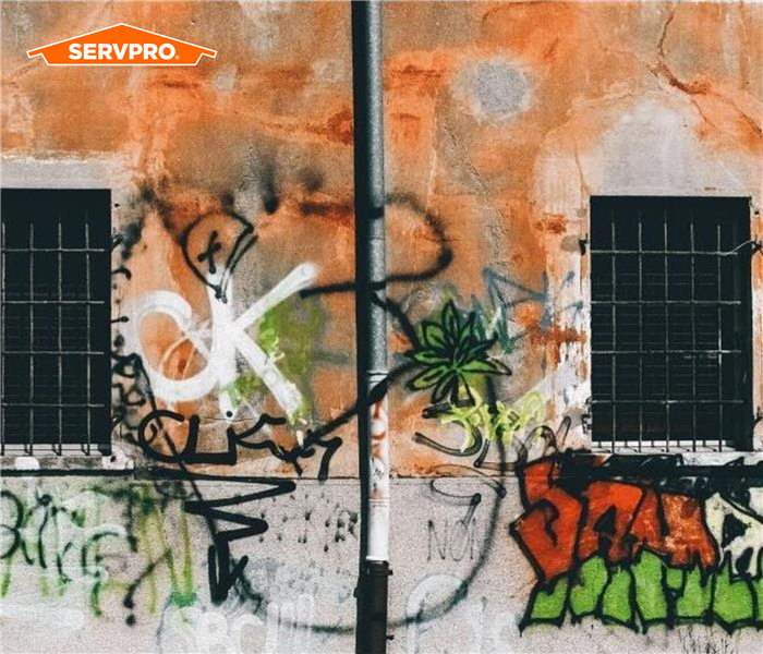 colorful spray painted graffiti on wall, orange SERVPRO logo in top left corner