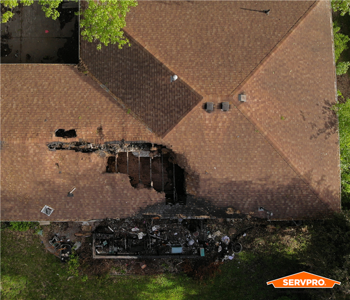 aerial view of a brown roof that has had fire damage, orange SERVPRO logo on image